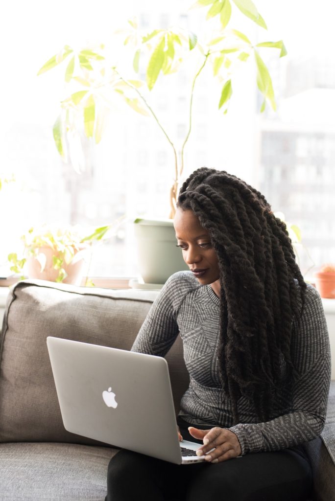 Woman of color on couch with laptop